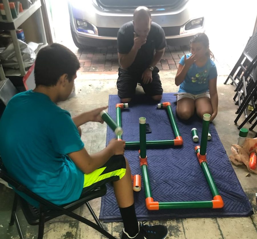 Tyler and his family assembling a strike zone frame on the garage floor